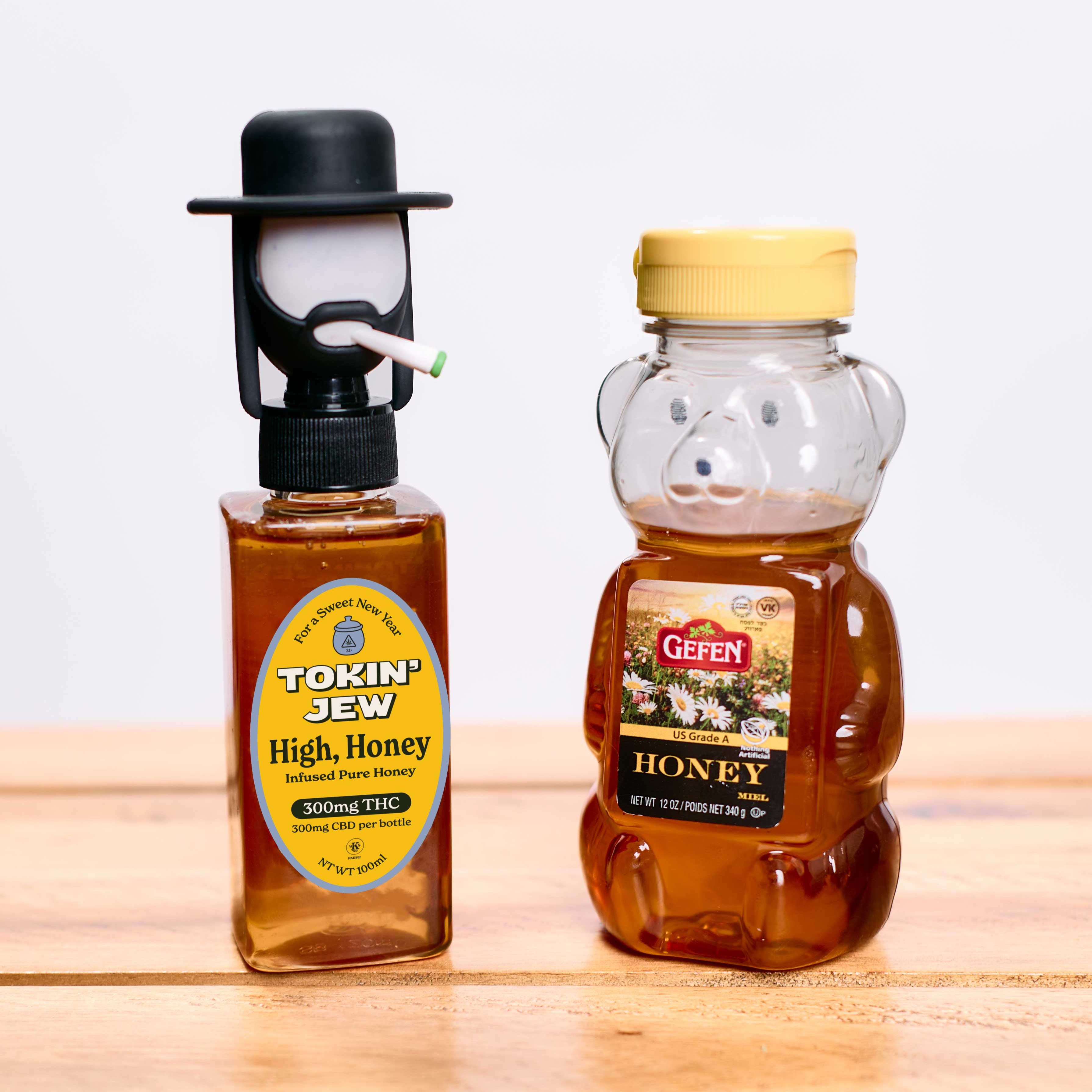 Two bottles of honey, one labeled 'Tokin' Jew High Honey' and the other 'Gefen Honey', on a wooden surface.