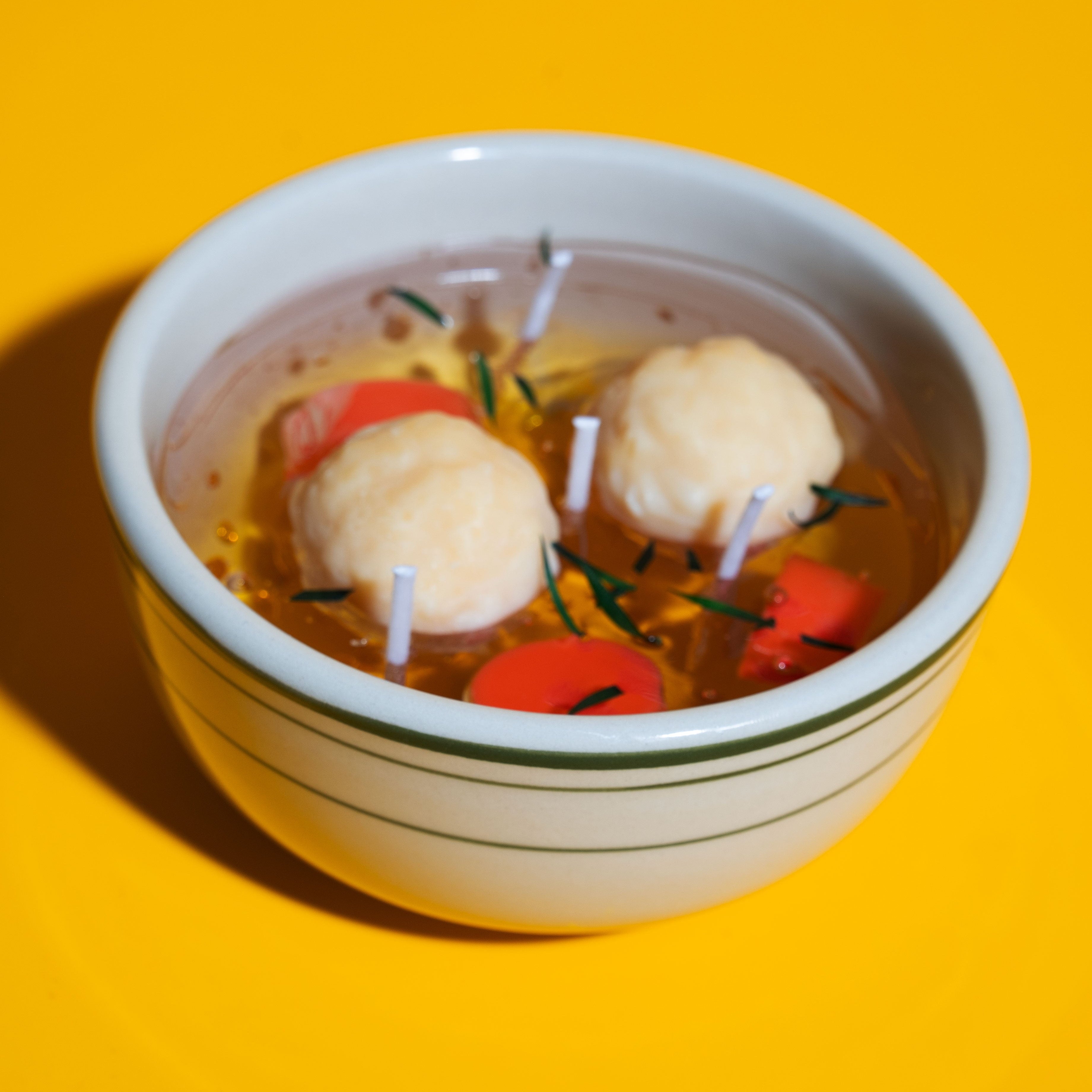 Matzo ball soup candle on a yellow background.