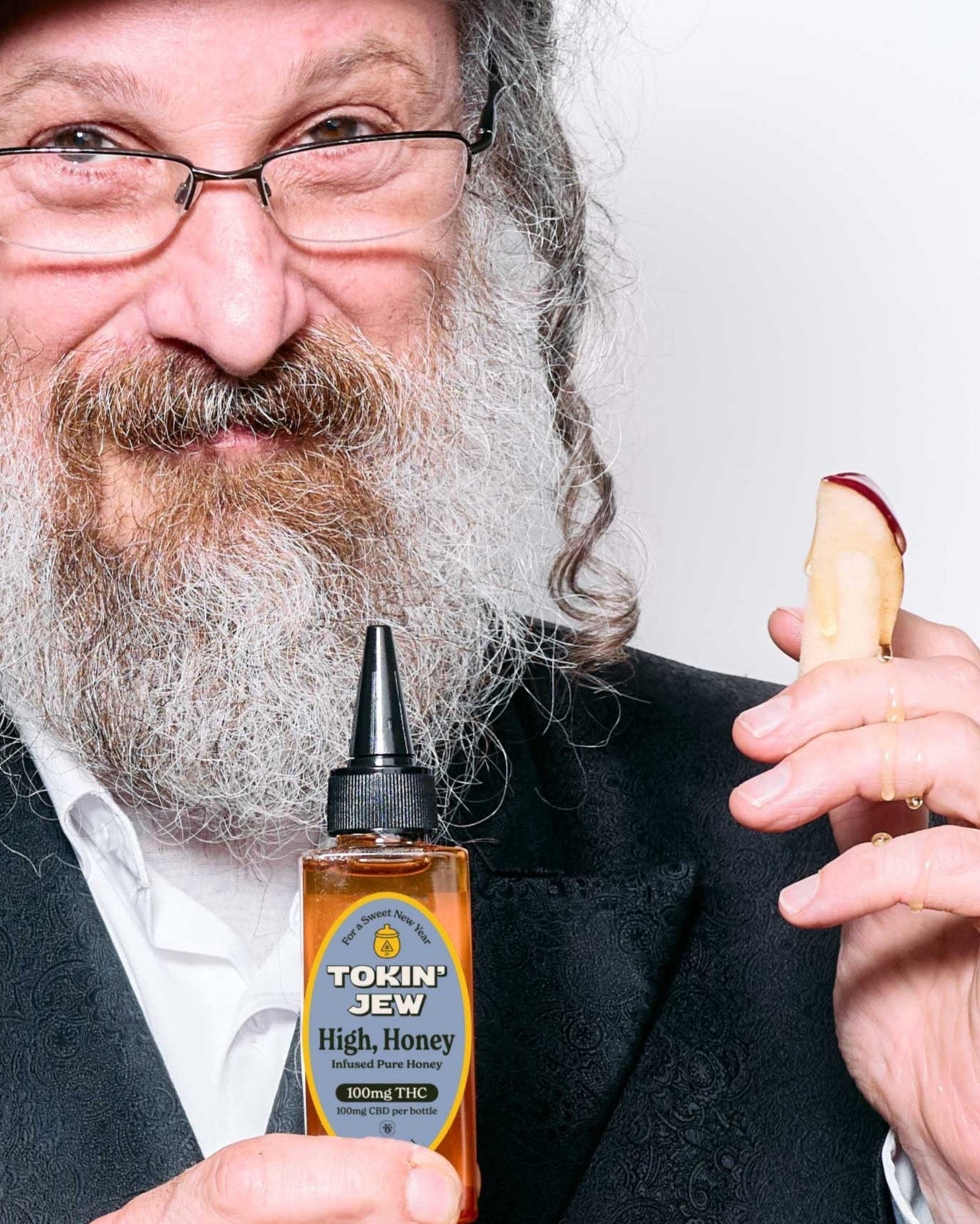 Man holding a bottle labeled 'Tokin' Jew High Honey' and a wooden container.