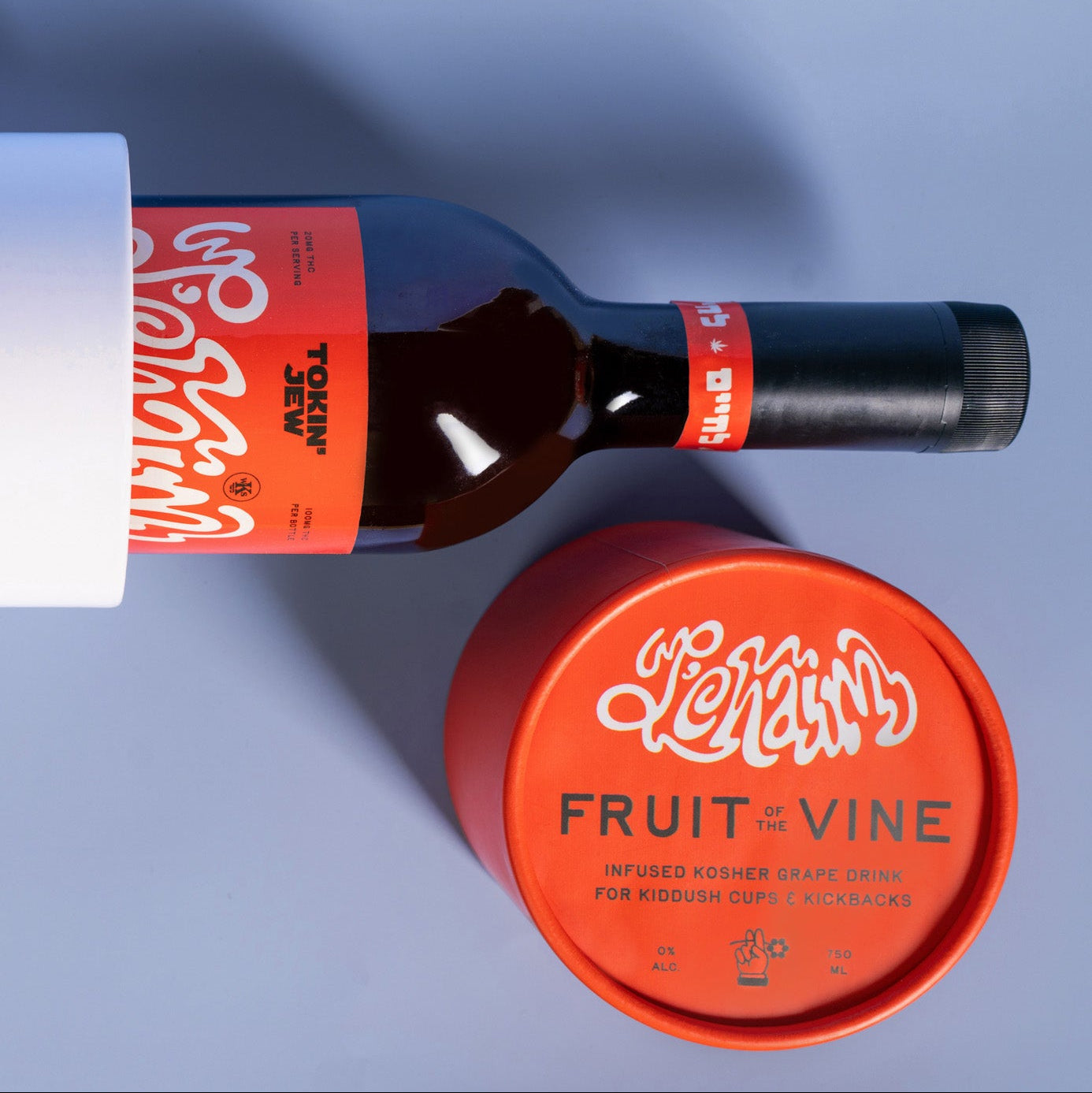 A bottle of Fruit of the Vine infused Kosher grape drink, shown with its bright orange label and matching orange lid on a cool blue-gray background.
