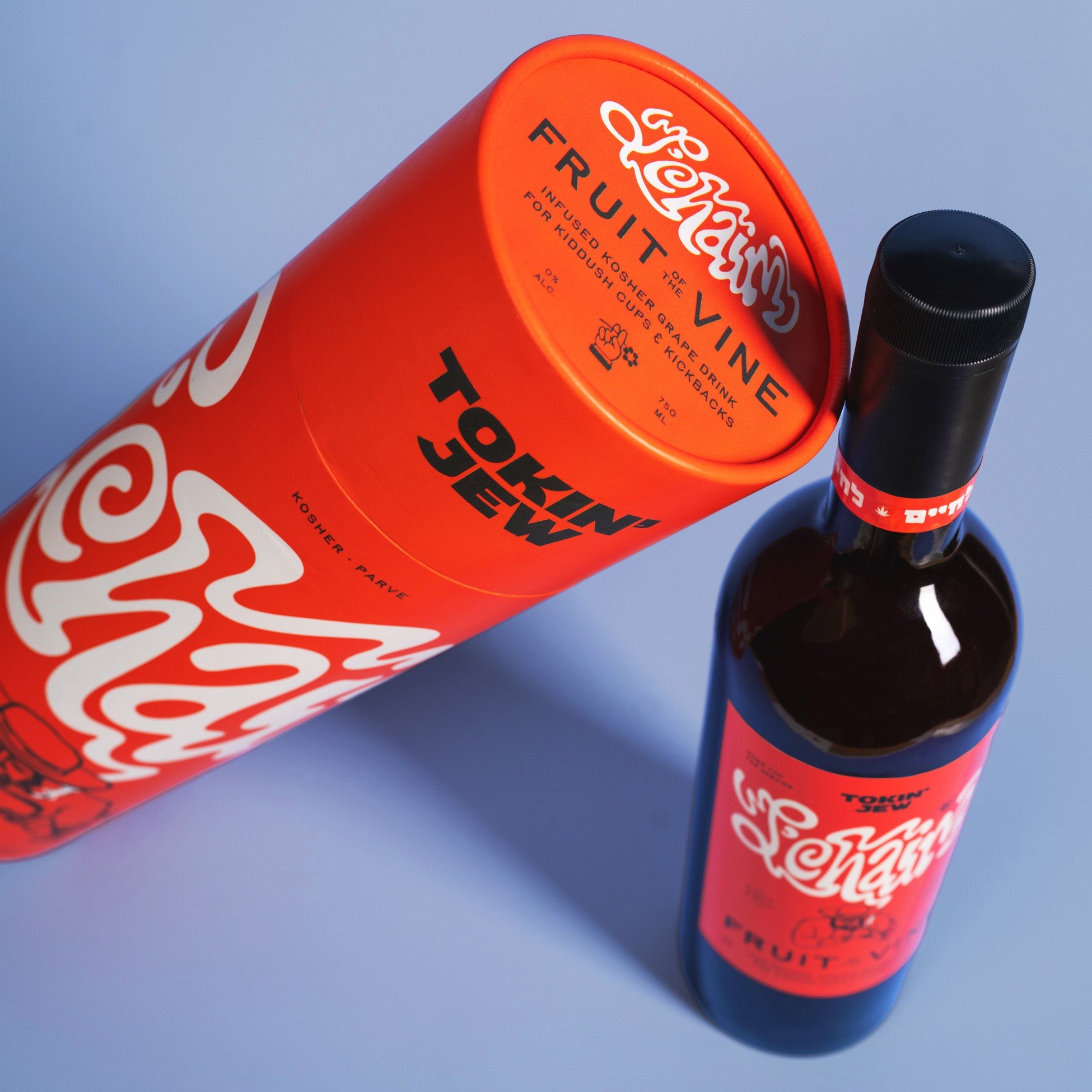 A bottle of Tokin Jew Fruit Vine spirit next to its bright orange cylindrical packaging tube, styled on a light blue background.
