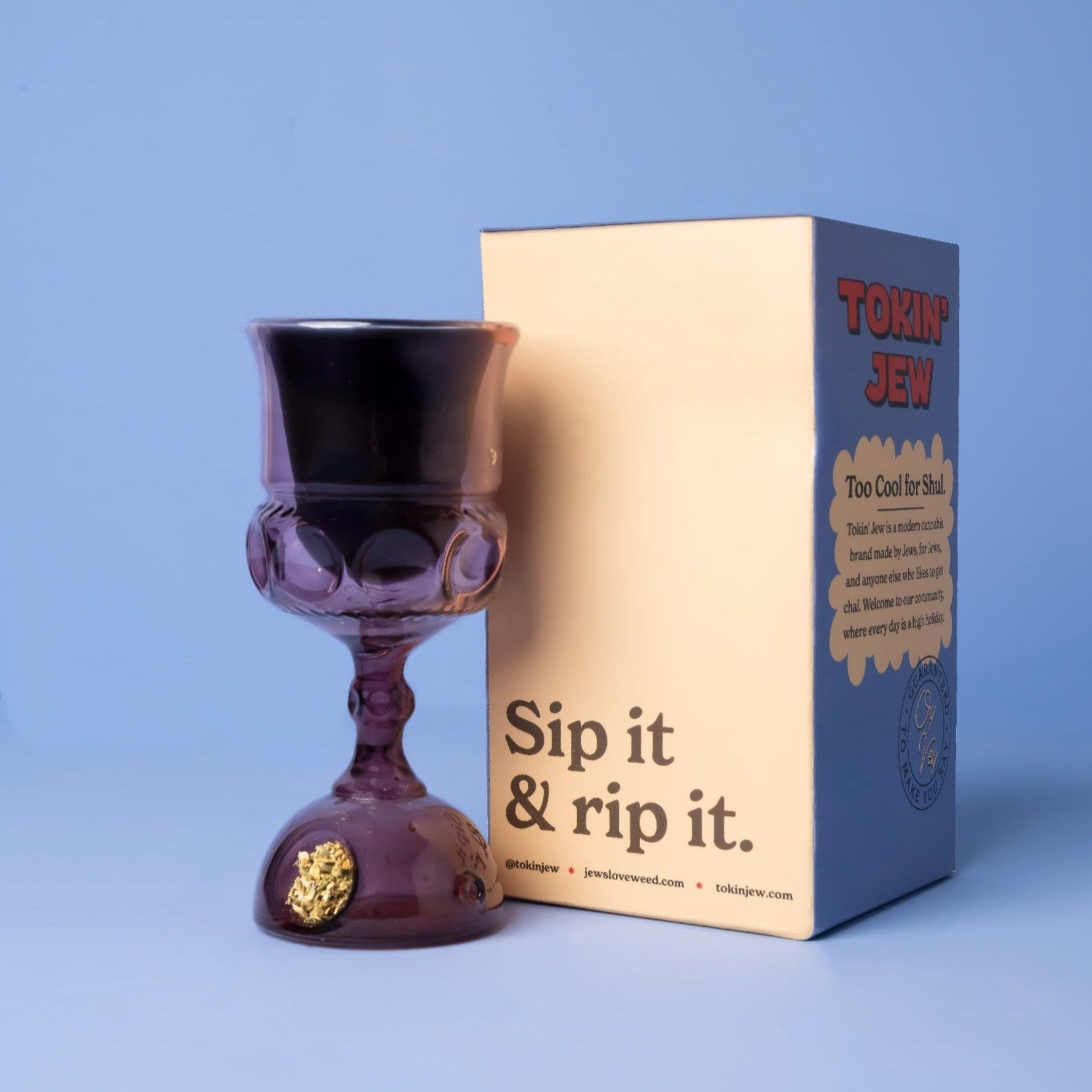 Purple kiddush cup next to its packaging on a blue background