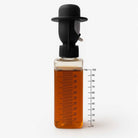 honey Bottle with a black cap filled with orange liquid on a white background