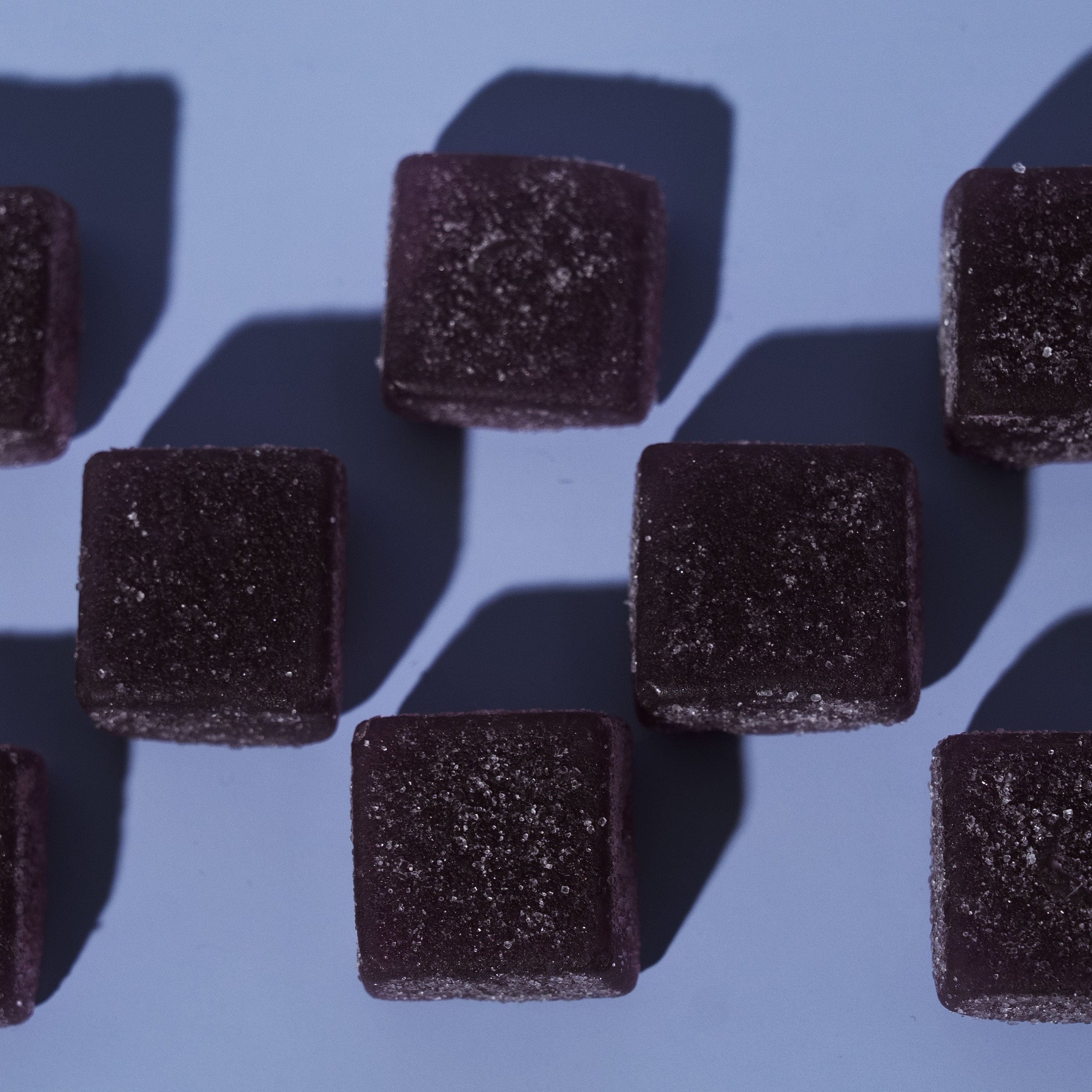 Dark purple square-shaped gummies on a blue background