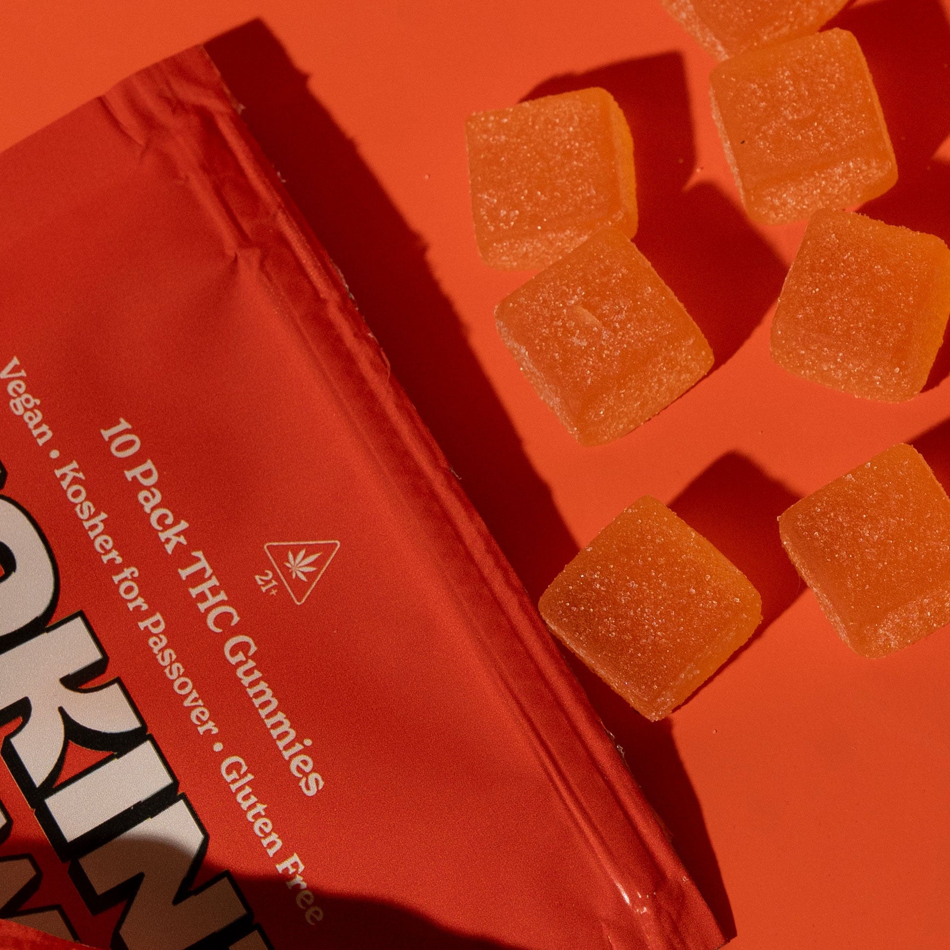 orange packaging of Token Chewy gummies with scattered gummies on an orange background