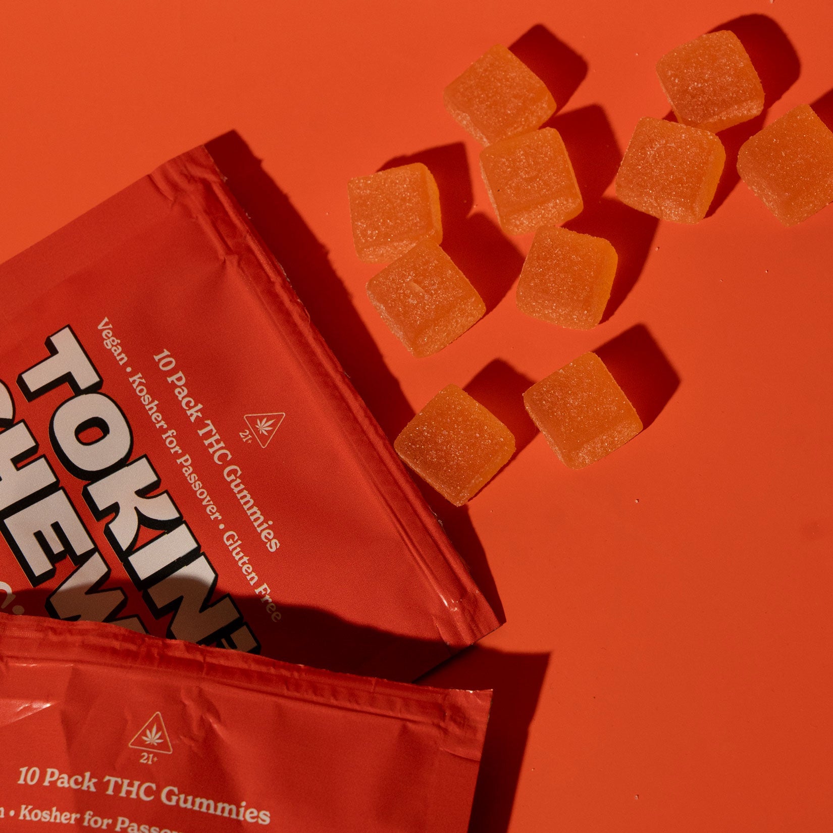 Two orange 'Tokin' Chews' packages with THC gummies on an orange background