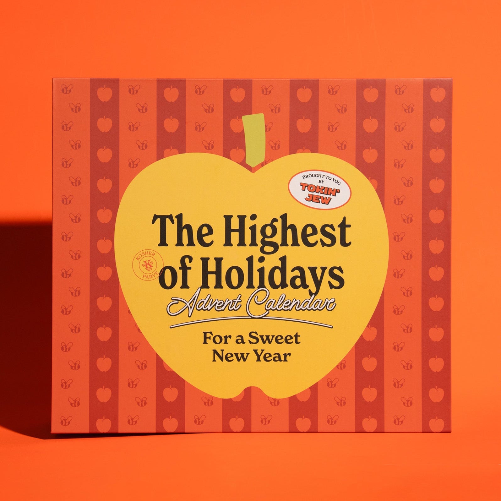The Highest of Holidays Advent Calendar for a Sweet New Year, featuring a bright yellow apple-shaped cover with black text, set against a patterned background of red and orange stripes with small holiday motifs.