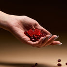 hand holding pomegranate seeds and 2 pomegranate gummies 