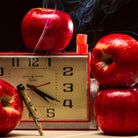 Vintage clock with red apples and a lit cigarette on a dark background
