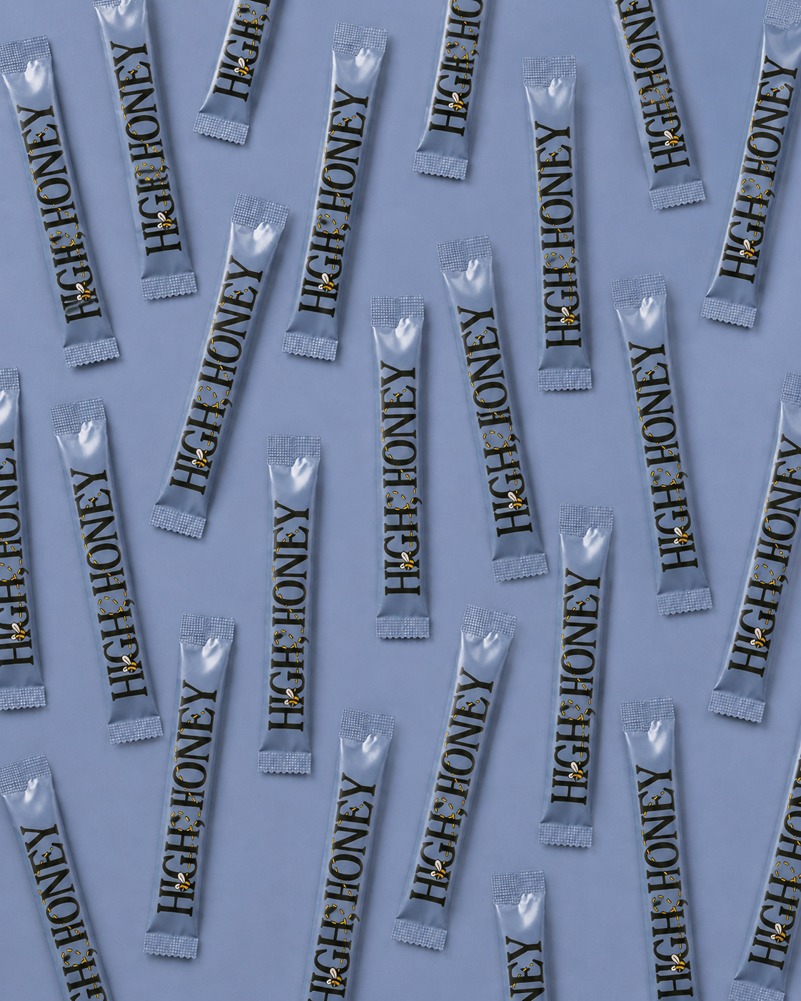 Multiple foil packets of High Honey candy arranged diagonally on a light blue-gray background.
