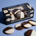 A box of Tokin' Jew Black & White Cookies on a solid blue background, with several cookies displayed in front of the package.