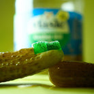 Jar of pickles with a pickle gummy on a yellow-green background
